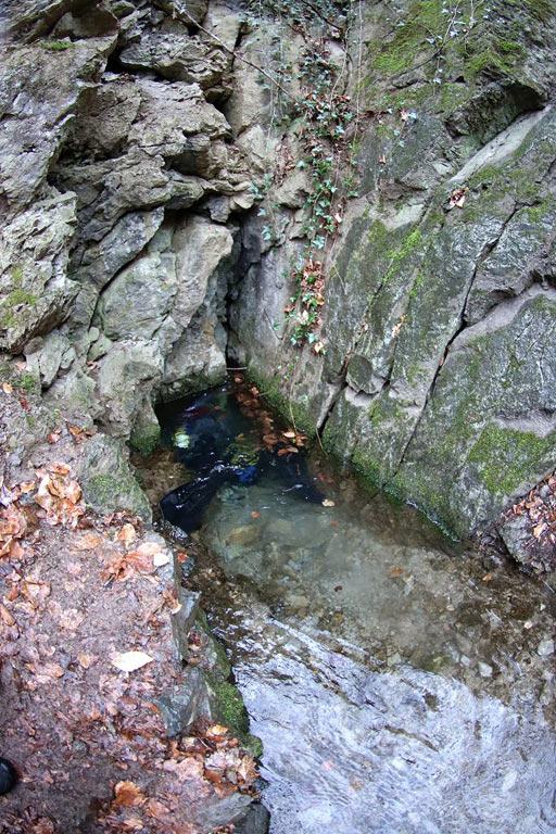 Na ponor do takého malého priechodu treba mať jaskyniarsku vášeň. Z potápača vidno len nohy s plutvami